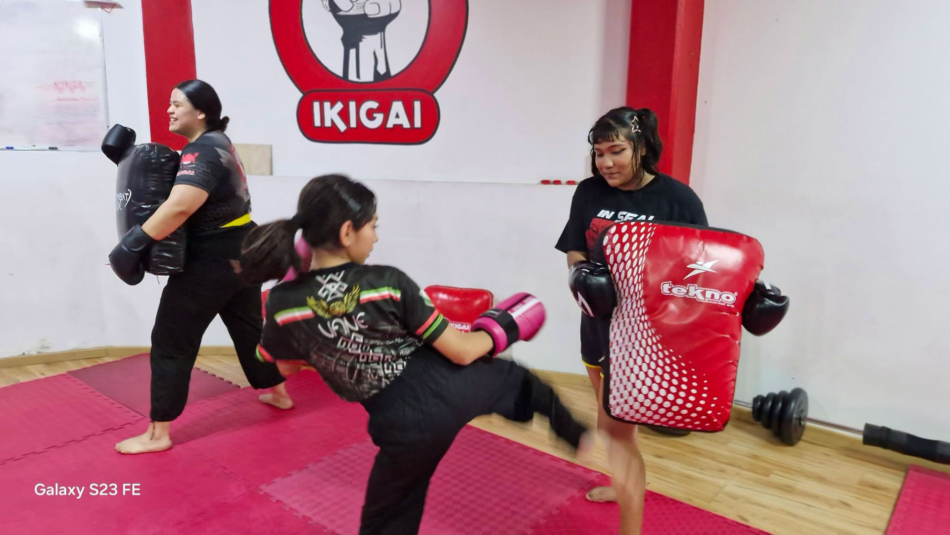 Alumnas entrenando kickboxing con paos en la clase de mujeres